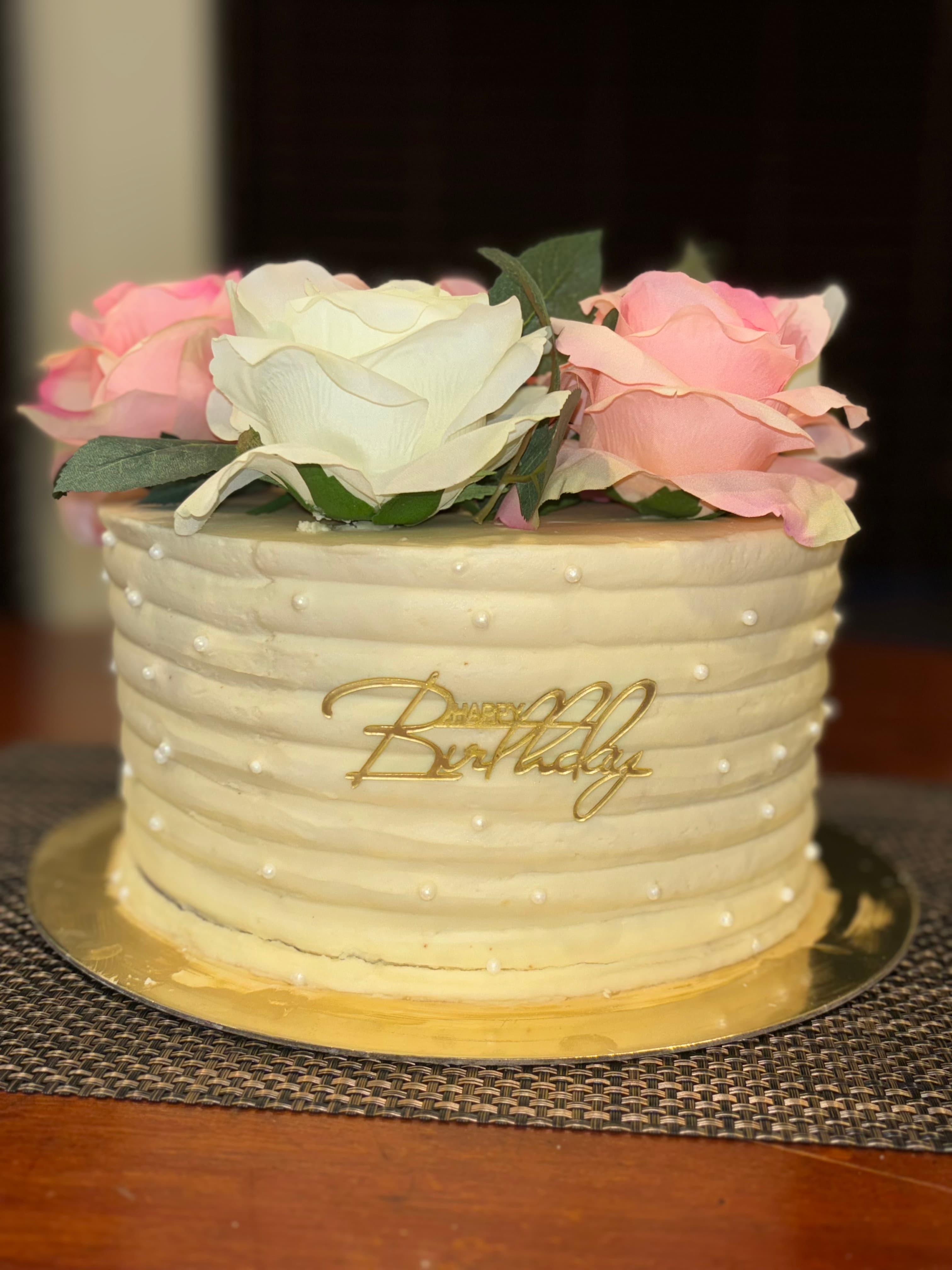 Cream ribbed buttercream cake with pink and white roses, gold script
